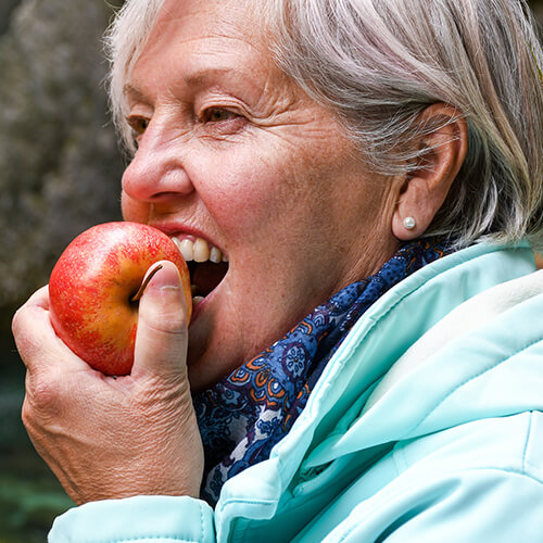 Woman biting into an apple, thanks to dental implants